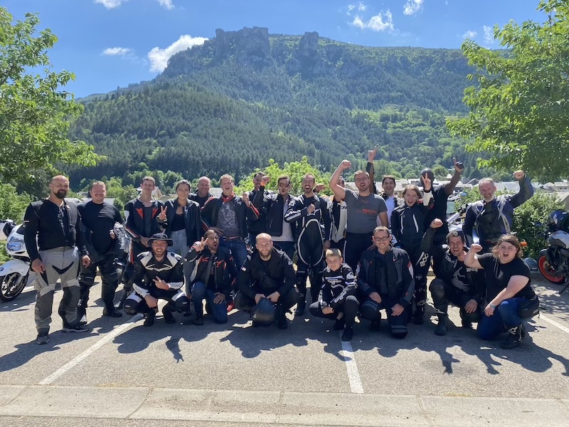 Groupe de motards de l'association #MONKEYPRORIDER posant devant leurs motos au pied d'une montagne