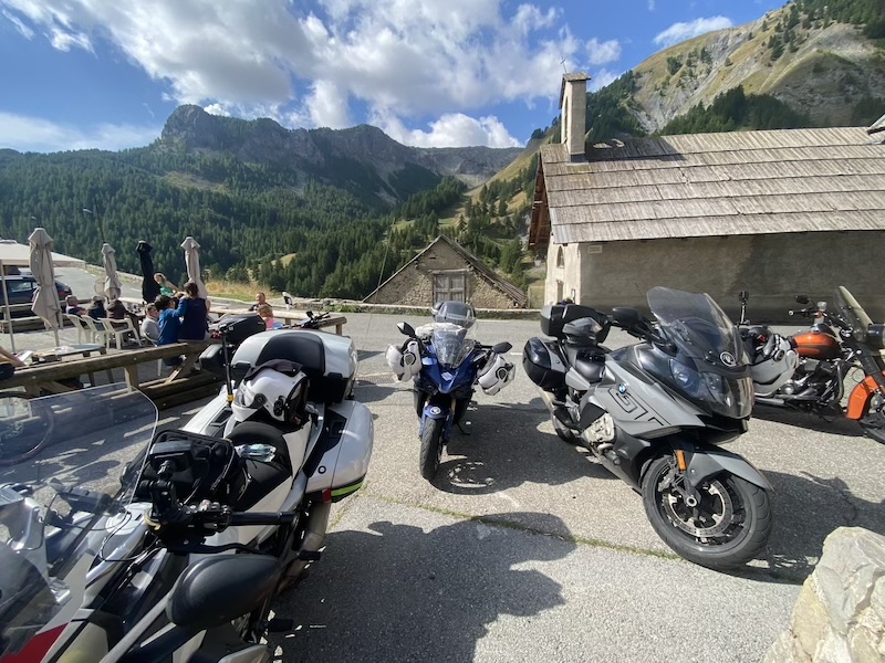 Motos de tourisme garées devant un chalet en pierre au pied des montagnes lors d'une sortie de l'association