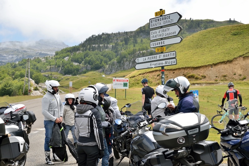 Motards de l'association arrêtés à un carrefour de montagne près d'un panneau indicateur pendant une balade